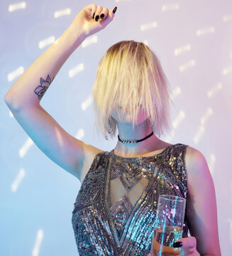 Portrait of unrecognizable young woman with face hidden behind her hair holding glass of champagne dancing