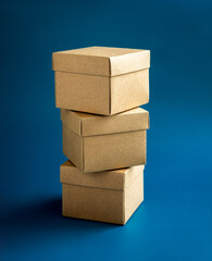 Three cardboard parcel boxes stack on blue background, vertical style. Carton kraft paper box with...