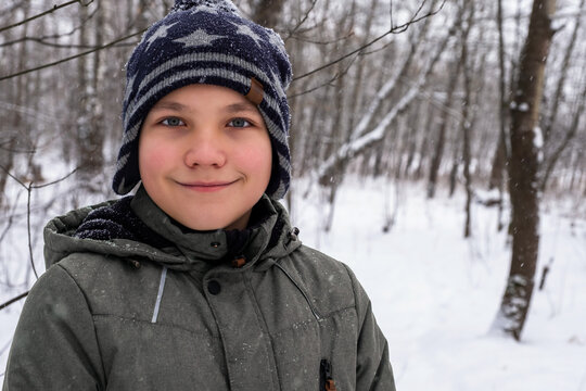 portrait of a smiling boy on the background of a winter forest