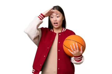Young basketball player asian woman over isolated background doing surprise gesture while looking to the side