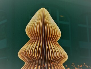 Abbildung von Weihnachtsbaum mit goldbrauner Pappe hinter Glasscheibe mit Spiegelung von...