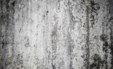 A weathered concrete wall with cracks and peeling paint, showing signs of age and decay.