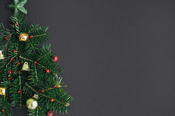 Stylish christmas tree made of fir branches, red berries and gold baubles on black background. Creative christmas idea, winter holidays. Merry Christmas! Modern festive flat lay, space for text