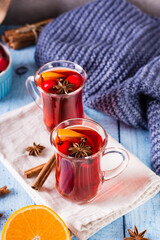 Homemade hot mulled wine with orange, cinnamon and berries in glasses on the table. Vertical view