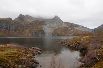 In einem Bergsee bei Reine in Norwegen spiegelt sich bei bewölktem Wetter die Landschaft