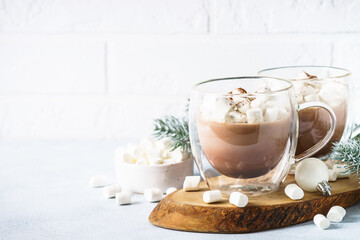 Hot chocolate with marshmallow in glass mug and christmas decorations.