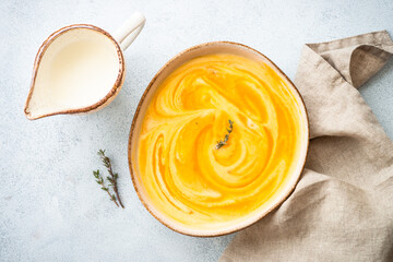 Pumpkin soup with cream in the craft bowl at stone table. Healthy eating. Top view with copy space.