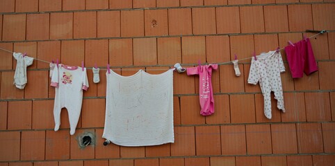 querformat, wäscheleine mit Babywäsche an einer Ziegelwand, neugeborenes kind, grußkarte