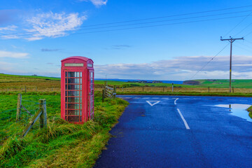 Red phone box, in landscape of fields, Orkney Islands