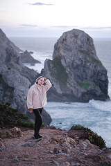 A woman stands on the rocks of the coast near Cabo da Roca, Portugal.