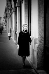 A woman stands on the sidewalk. Black and white photo.