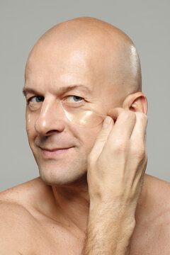 Studio portrait shot of charismatic mature man treating his under-eye skin with collagen patches looking at camera