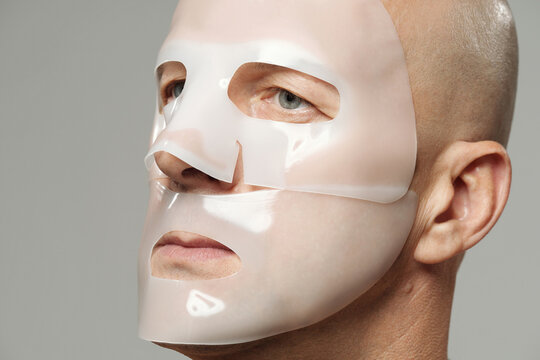 Mature man using moisturising hydrogel collagen mask on face looking away 
