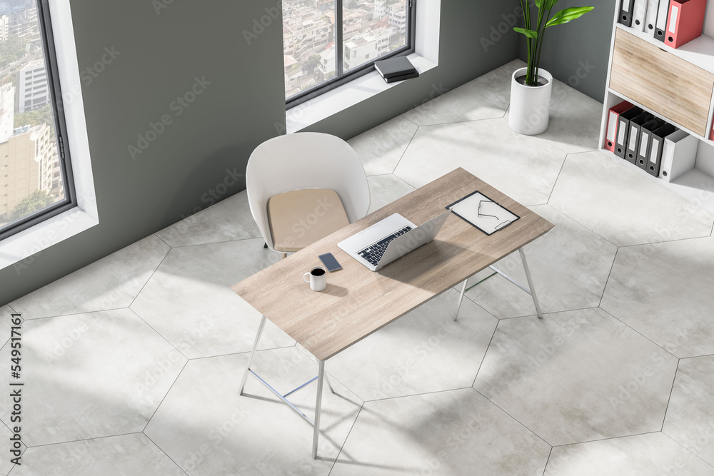 Poster top side view on stylish wooden work table with laptop on concrete floor in spacious sunlit home off