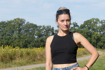 Young woman in summer park enjoying nature and bright sun. Place for text