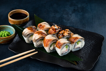 Japanese sushi rolls with smoked eel, shrimps, cream cheese, avocado, soy sauce and wasabi.
