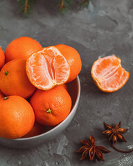 Bowl with fresh bright mandarine oranges on a grey background. Peeled tangerine. Healthy eating concept.