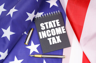 On the American flag lies a pen and a notebook with the inscription - state income tax