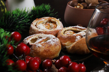 Puff rolls with raisins and chocolate cream in a black plate on the Christmas table, New Year. close-up