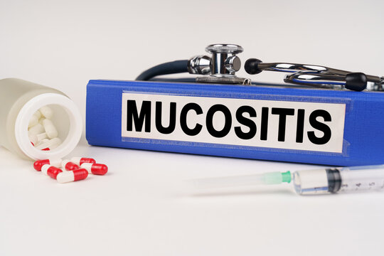On a white surface there are pills, a syringe and a folder with the inscription - Mucositis