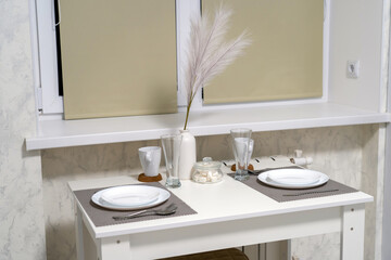 Setting table for dining room, white wooden table is decorated with feathers