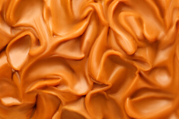 Liquid melted caramel syrup. Background of caramel syrup, paste. Curl, wave of caramel. Texture, Close up, top view.