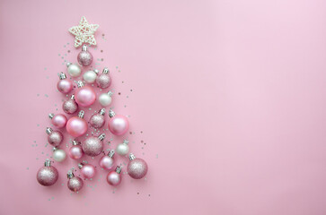 Christmas tree made of stars, confetti, pink balls on pink background. Flat lay, top view. Xmas greeting card with text - Merry Christmas.