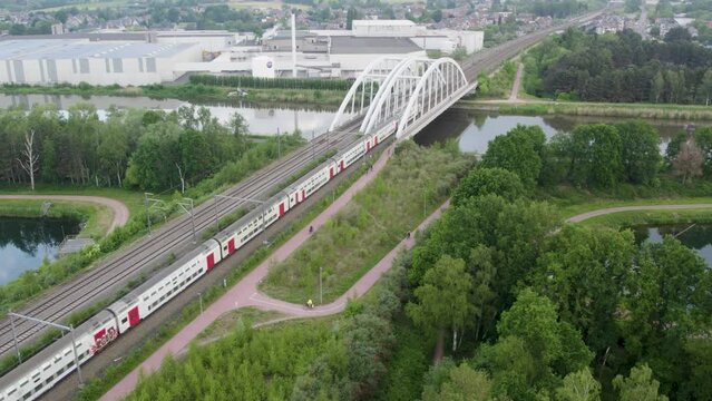 Aerial view shot by a drone of a train passing by on the railway track and over a bridge across a river in Belgium . High quality 4k footage