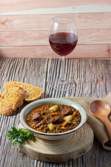 Traditional lentil stew with legs, carrots, chorizo and a glass of red wine. Mediterranean cuisine