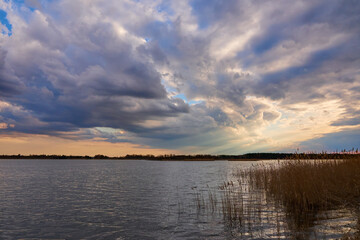 Cloudy afternoon over a lake. Epic clouds on sunset.