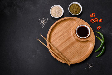 Empty plate with wooden sticks for Asian food on a dark concrete background