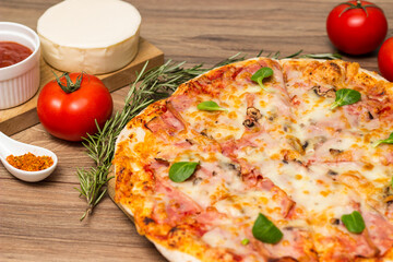 Freshly baked pizza with ham, tomato, and cheese