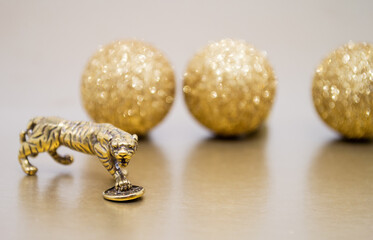 A bronze figure of a tiger with a coin on a background with golden shiny balls, copy space. Wishes...