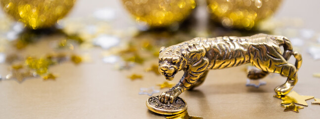 Banner with bronze figure of a tiger with a coin on a background of stars, golden shiny balls, copy space
