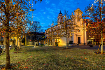 Catholic church on town square illuminated with Christmas lights in Alba, Italy.