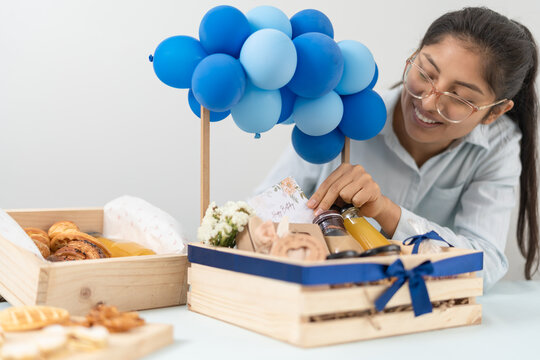 Happy woman preparing present boxes with blue balloons