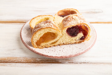 Homemade sweet bun with apricot jam on white wooden. side view.
