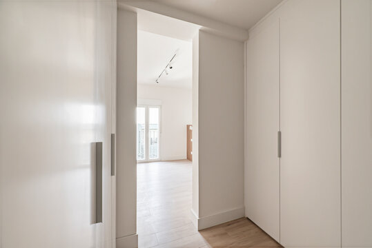 Bedroom with a dressing room with smooth wooden doors with gray handles and white sconces on the ceiling