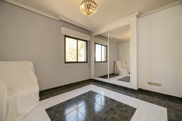 Living room with a crystal lamp on the ceiling, a plaster molding and a seat with fabrics, a built-in wardrobe with sliding mirror doors and a combined stoneware floor