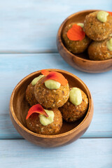 Falafel with guacamole on blue wooden. Side view.