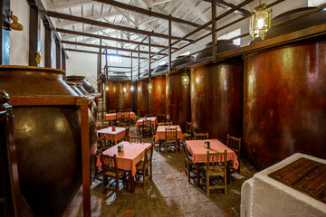 A dining room of an old restaurant with clay vats filled with wine