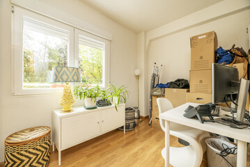 Fototapeta na wymiar A cluttered room with white furniture and a window overlooking a garden