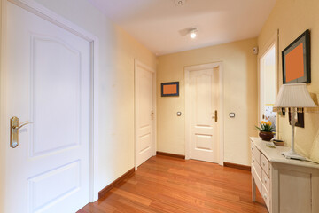 Distributor corridor of urban housing with jatoba wood parquet floors and white lacquered wood access doors to the rooms