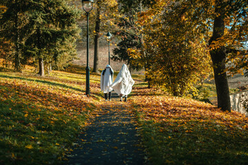 A funny image of two walking people in ghost costumes and sunglasses