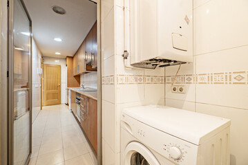 A kitchen with a room for the washing machine and a natural gas boiler