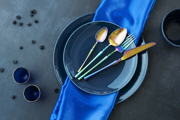 Various blue china plates with blue tablecloth, gold-rimmed blue glasses, blueberries, and...