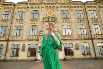 Fototapeta na wymiar Low angle shot of an elegant woman wearing green dress, walking city streets