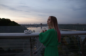 Obraz premium Rear view shot of a beautiful female tourist enjoying sunset view of a river in the city