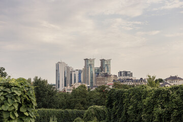 Green lawn with modern buildings as background. Green field in big city park. Park landscape. High apartment buildings in the back under a cloud scape.