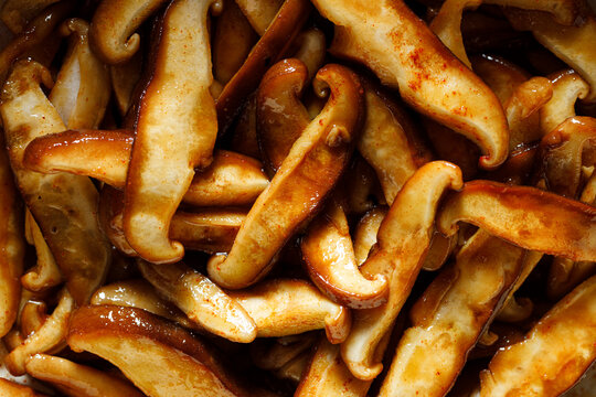 Sliced shitake mushrooms in an aromatic marinade, close up view
